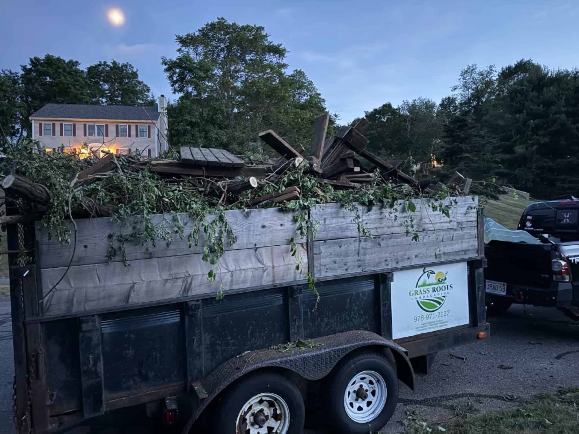 Grass Roots trailer loaded with branches and debris at dusk